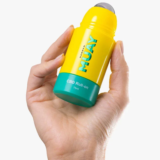 Main tenant un roll-on CBD Muay 75ml jaune et vert, cosmétique naturel Alazina
