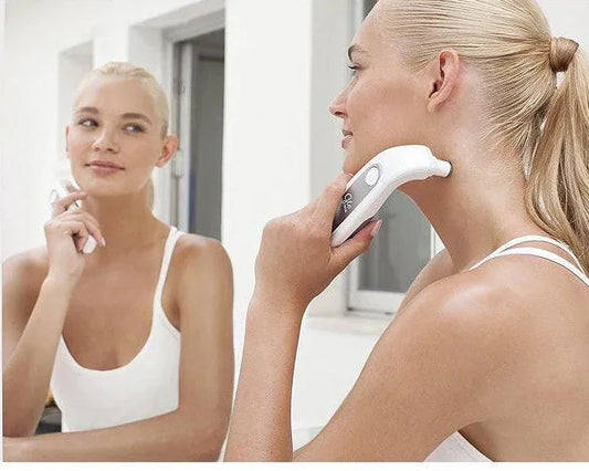 Femme utilisant un appareil microdermabrasion visage Glo Me dans une salle de bain lumineuse, soin beauté Alazina.